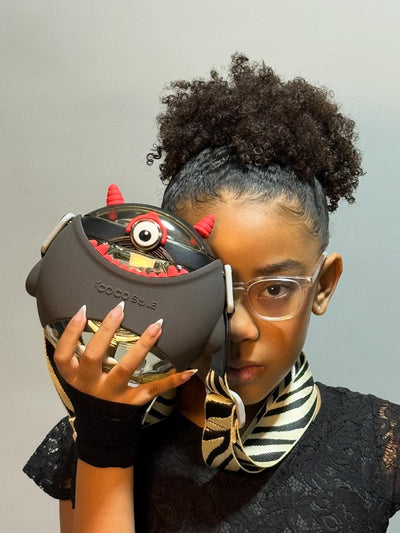 Person holding a unique helmet with a red and black design against a neutral background